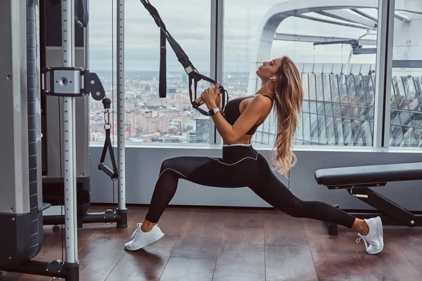 Hermosa chica ejercicios con expansor de fitness en el gimnasio . — Foto de Stock