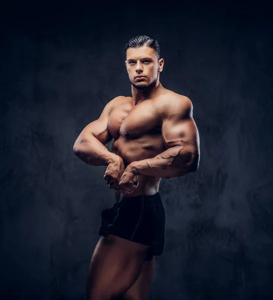 Un hombre atlético guapo con cuerpo muscular de pie en pose competitiva culturista —  Fotos de Stock