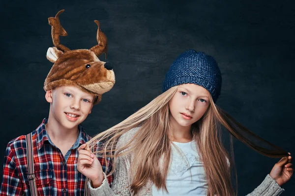 Портрет девушки в зимней шляпе и улыбающегося мальчика в оленьей шляпе, смотрящего в камеру — стоковое фото