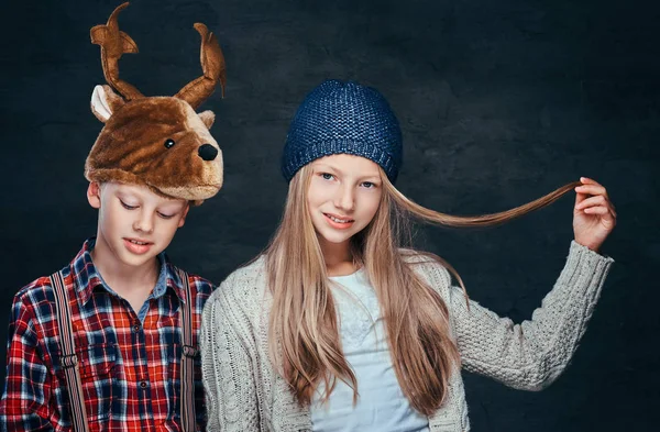 Porträtt av en leende flicka i vintermössa och söt pojke i rådjur hatt. — Stockfoto