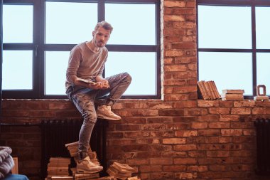 Genç yakışıklı öğrencisi şık sakal ve bir kitap ve kameraya bakarak saç