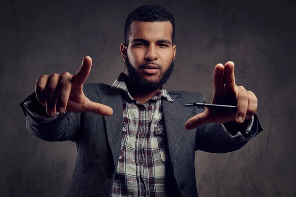 Afro-americano cara está posando ao lado de um escuro texturizado parede . — Fotografia de Stock