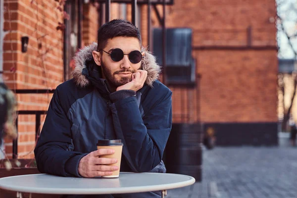 Un joven guapo bebiendo café al aire libre . — Foto de Stock