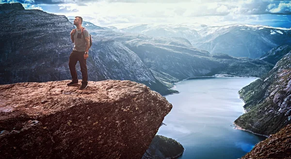 Homem turístico de pé na Trolltunga e desfruta de uma bela vista do fiorde norueguês . — Fotografia de Stock