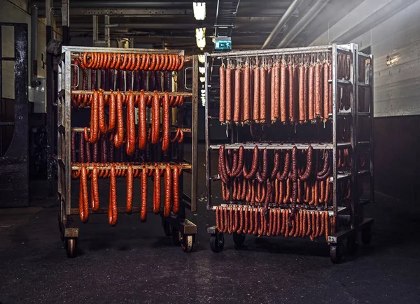 Embutidos en bastidores en un almacén en una fábrica de procesamiento de carne . —  Fotos de Stock