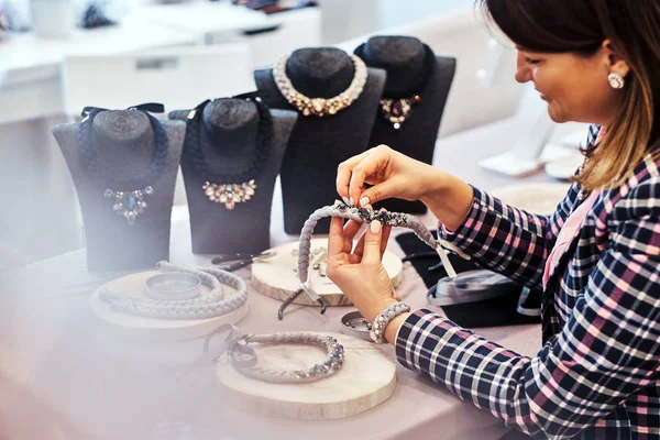 Mujer elegantemente vestida hace collares hechos a mano, trabajando con agujas e hilo en el taller . —  Fotos de Stock