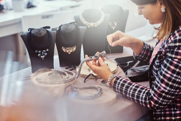 Elegantně oblečená žena dělá ručně vyráběné náhrdelníky, práce s jehel a nití v dílně. — Stock fotografie