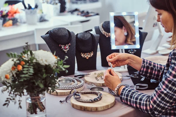 Mujer elegantemente vestida hace collares hechos a mano, trabajando con agujas e hilo en el taller . —  Fotos de Stock