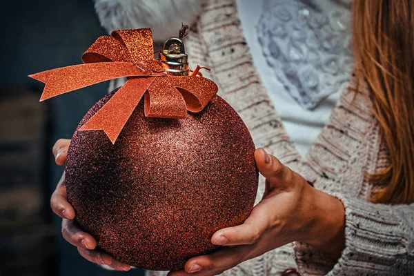 Loseup foto de una bola roja de Navidad en las manos de una adolescente —  Fotos de Stock