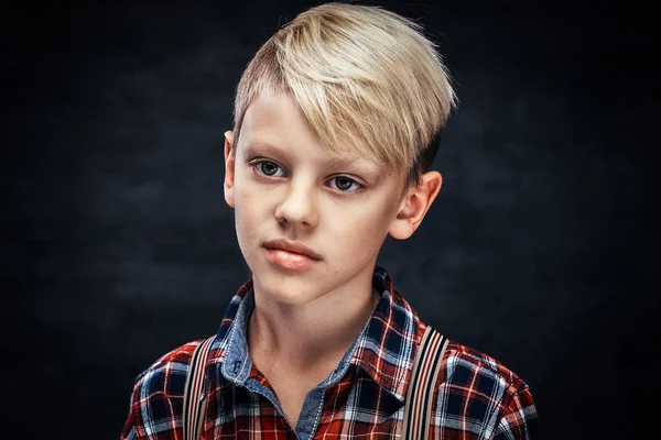 Een knappe tiener jongen dragen een geruite shirt met bretels. — Stockfoto