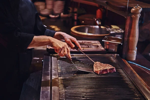 Master chef cooking delicious beef steak on a kitchen in a restaurant.