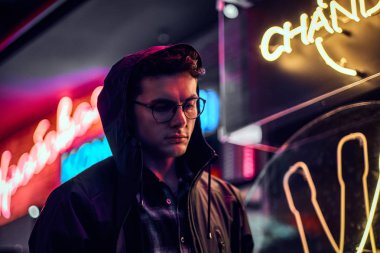 Gece sokakta duran yakışıklı bir genç adam. Işıklı tabela, neon, ışıklar.