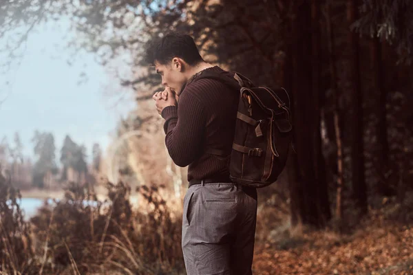 Un jeune randonneur portant un pull réchauffe les mains dans la forêt froide d'automne . — Photo