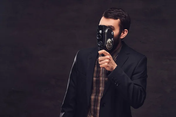 Retrato del estudio del hombre barbudo con un traje clásico sosteniendo una cámara retro, haciendo una foto . —  Fotos de Stock