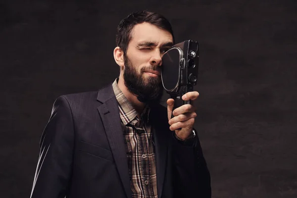 Retrato del estudio del hombre barbudo con un traje clásico sosteniendo una cámara retro, haciendo una foto . — Foto de Stock