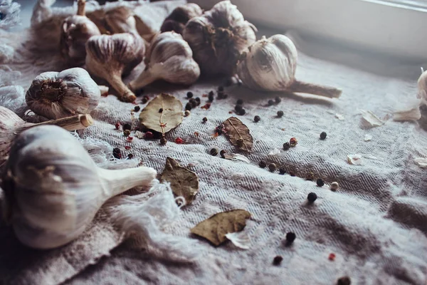 Foto dei frutti di pepe nero, foglie di alloro, aglio sparsi su un foglio di tessuto — Foto Stock