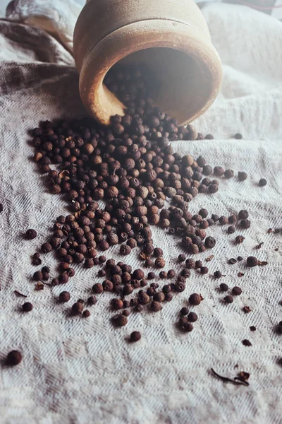 Foto van een mortier en een verspreide zwarte peper op linnen stof — Stockfoto