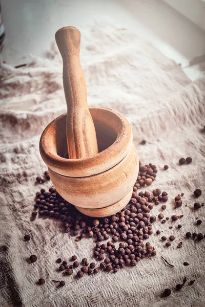 Photo of a mortar and scattered black pepper on linen fabric — Stock Photo, Image