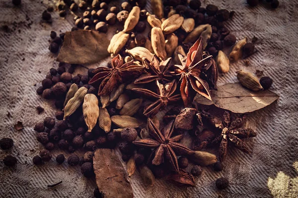 Pimienta negra dispersa, frijoles, canela y hojas de laurel sobre tela de lino —  Fotos de Stock