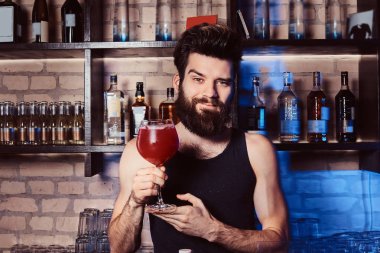 Aperol spritz ile bir bardak kokteyl bar sayaç bir kamera için poz süre tutarak yakışıklı sakallı barmen