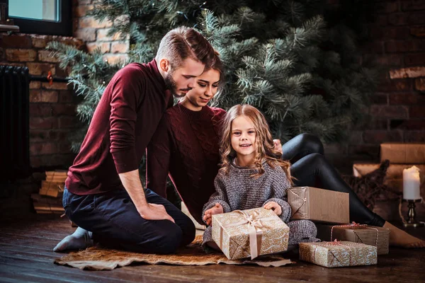 Çekici aile hediyeleri Noel ağacının yanındaki bir katta otururken açar. — Stok fotoğraf