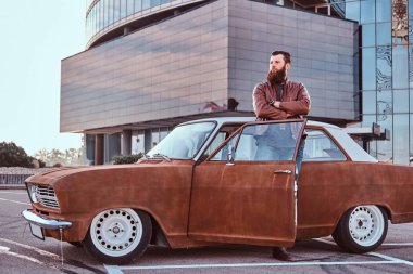 Eski moda giysiler ayarlanmış bir eski retro araba gökdelen Park City açık kapı ile eğilerek şık sakallı erkek.