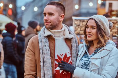 Noel zamanda sokakta yürüyen genç romantik bir çift ayakta yakınındaki dükkanlar akşam, birlikte vakit zevk dekore.