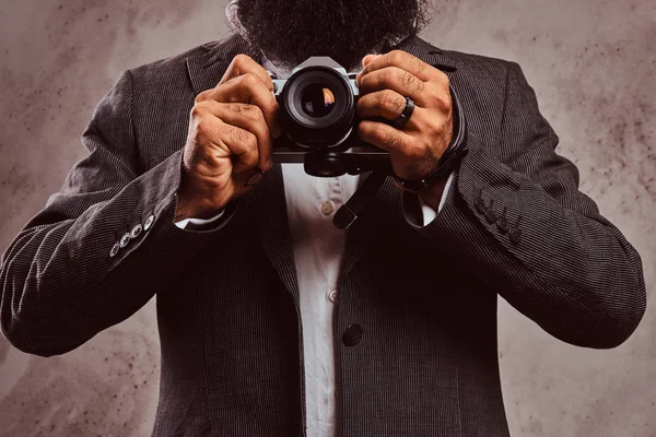 Imagen recortada de un hombre barbudo usando traje formal sosteniendo una cámara . — Foto de Stock