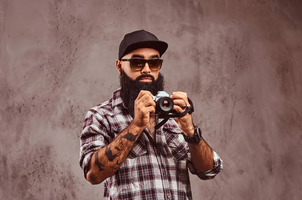 Yakın çekim kareli gömlek güneş gözlüğü ve bir kamera tutarak kap giyen sakallı bir Arap Erkek portresi. 