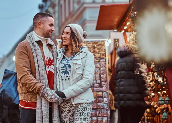 A happy romantic couple holding hands while standing on the street at Christmas time, enjoying spending time together. — Stock Photo, Image