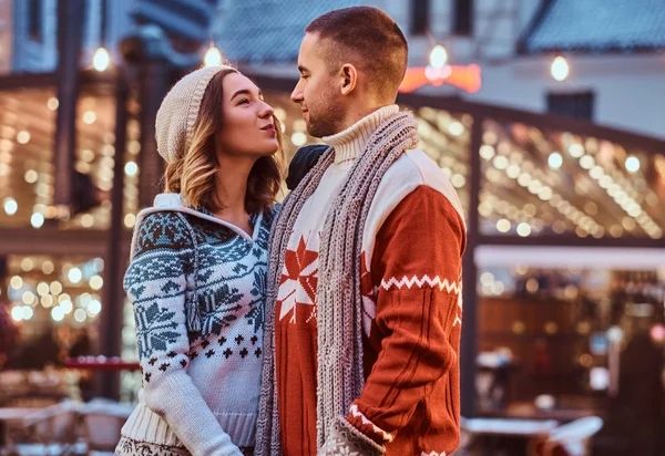 Una joven pareja romántica tomados de la mano y mirándose mientras están en la calle en Navidad, disfrutando pasar tiempo juntos . — Foto de Stock