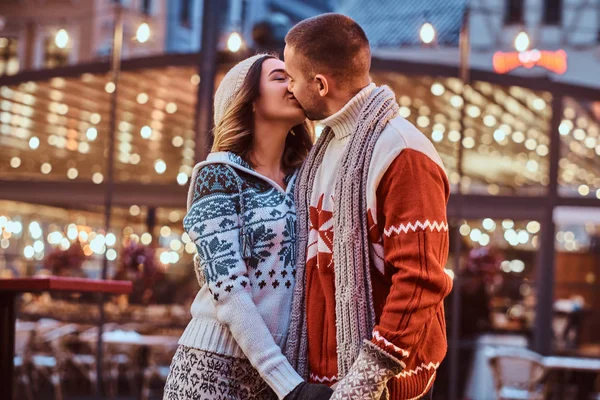 Una joven pareja romántica vistiendo ropa de abrigo cogida de la mano y besándose al aire libre por la noche, disfrutando pasar tiempo juntos . — Foto de Stock