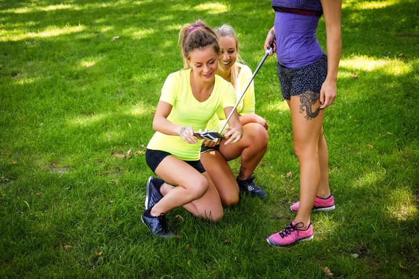 Tre amiche sportive al parco all'aperto guardando foto dopo selfie — Foto Stock