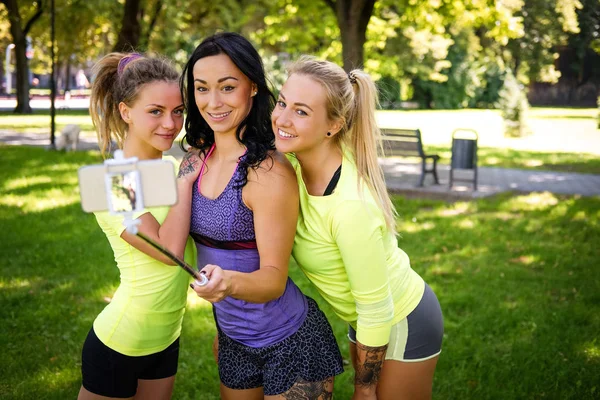 在户外公园里 三位运动中的女性朋友用棍子在电话里自拍 — 图库照片