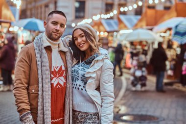 Sıcak giysiler Noel zamanı, akşam sokakta açık sarılma birlikte vakit zevk giyen genç bir romantik çift.