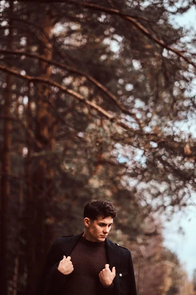 Joven con abrigo cubriéndose los hombros en el bosque otoñal . — Foto de Stock