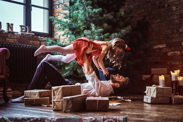 Dad and daughter have fun together while lying on the floor, surrounded by gifts near the Christmas tree — Stock Photo, Image