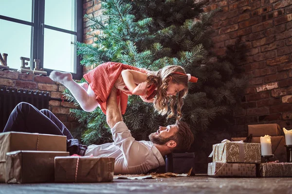 爸爸和女儿躺在地板上, 周围都是圣诞树附近的礼物, 他们在一起玩得很开心 — 图库照片