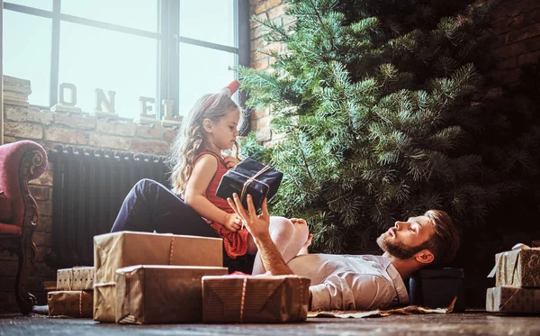 Dad and daughter lying on the floor, surrounded by gifts near the Christmas tree — Stock Photo, Image