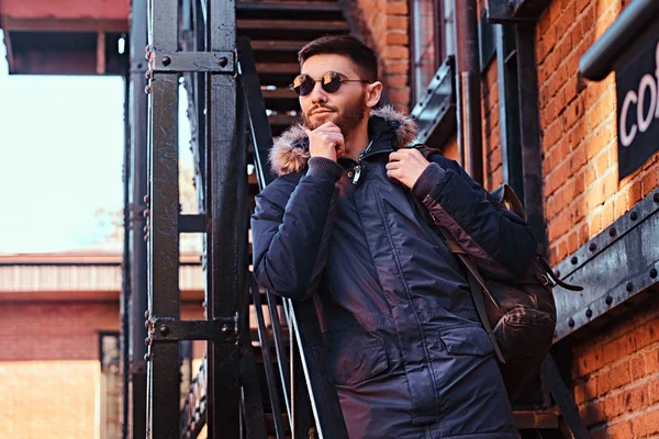 Een peinzende jonge man met een rugzak staande op de trap buiten. — Stockfoto