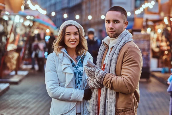 Młoda para romantyczny spaceru na ulicy, w okresie Bożego Narodzenia, stojący w pobliżu urządzone sklepy, wieczorem, ciesząc się, spędzać czas razem. — Zdjęcie stockowe