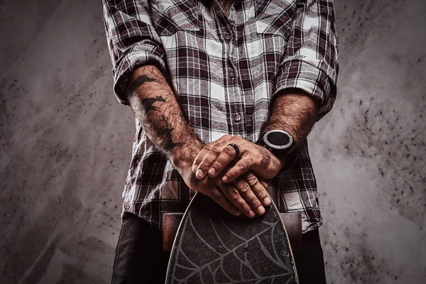 Gedeeltelijke weergave van een man die het dragen van een geruite shirt leunend op een skateboard. Geïsoleerd op een grijze achtergrond. — Stockfoto