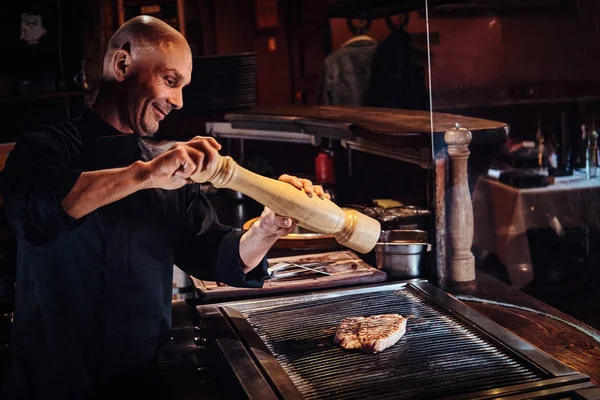 Ler kocken bär enhetlig matlagning läckra nötstek på ett kök i en restaurang — Stockfoto