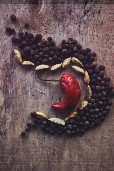 The composition of black pepper, beans and one red pepper in the middle — Stock Photo, Image