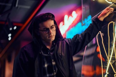 Dalgın bir genç adam sokakta bir ışıklı tabela üzerinde geceleri yaslanmış.