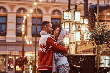 Sıcak giysiler Noel zamanı, akşam sokakta açık sarılma birlikte vakit zevk giyen genç bir romantik çift.