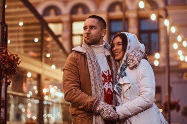 Sıcak giysiler Noel zamanı, akşam sokakta açık sarılma birlikte vakit zevk giyen genç bir romantik çift.