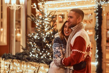 Noel zamanda açık sarılma sıcak giysiler giyen genç bir romantik çift