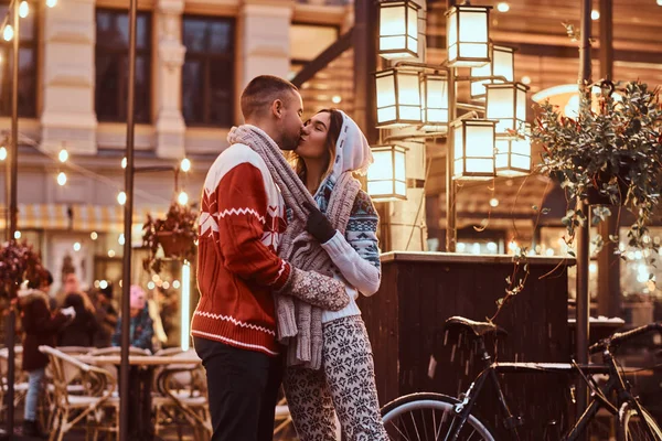 Una joven pareja romántica vistiendo ropa de abrigo cogida de la mano y besándose al aire libre por la noche, disfrutando pasar tiempo juntos . — Foto de Stock