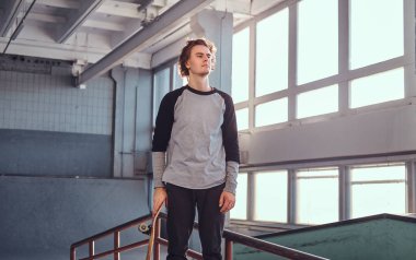 Holding onun yönetim kurulu ve uzağa bakarak skatepark kapalı, bir eziyet demiryolu yanında duran genç kaykaycı.